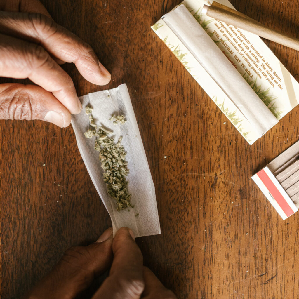 Ground Cannabis being rolled into RAW branded, hemp rolling papers to make a joint.